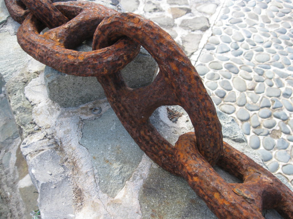 large rusted chain on cobblestones